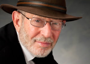 Alan Ellis wearing a dark sport coat and hat.