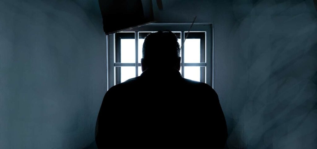 Man looks out window of jail.